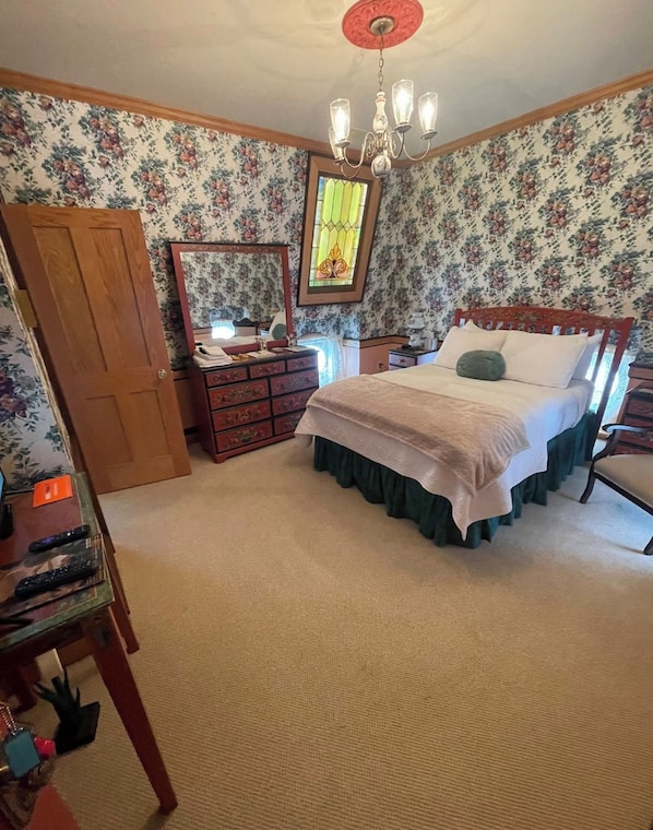 A bedroom with a bed, dresser, mirror, and a chandelier.