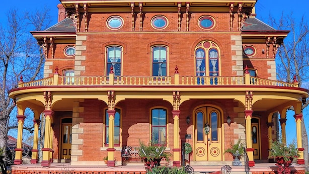 A large, two-story brick building with a balcony and multiple windows. - Escape to The Pella Mansion: Peaceful Countryside Estate, AC, Close to Pella, IA (Pella)