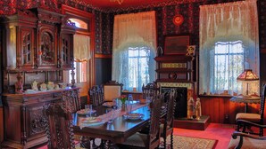 A dining room with a wooden table set for four, surrounded by ornate chairs. - Escape to The Pella Mansion: Peaceful Countryside Estate, AC, Close to Pella, IA (Pella)
