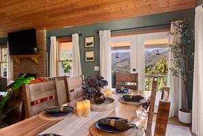A dining area with a table set for two, a television mounted on the wall, and a view of the outdoors. - Cozy Skylodge, Lake, Hot Tub, Mountain View, Games (Canton)