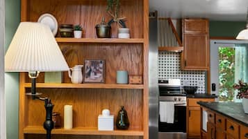 A kitchen with wooden shelves, a lamp, and a stove.