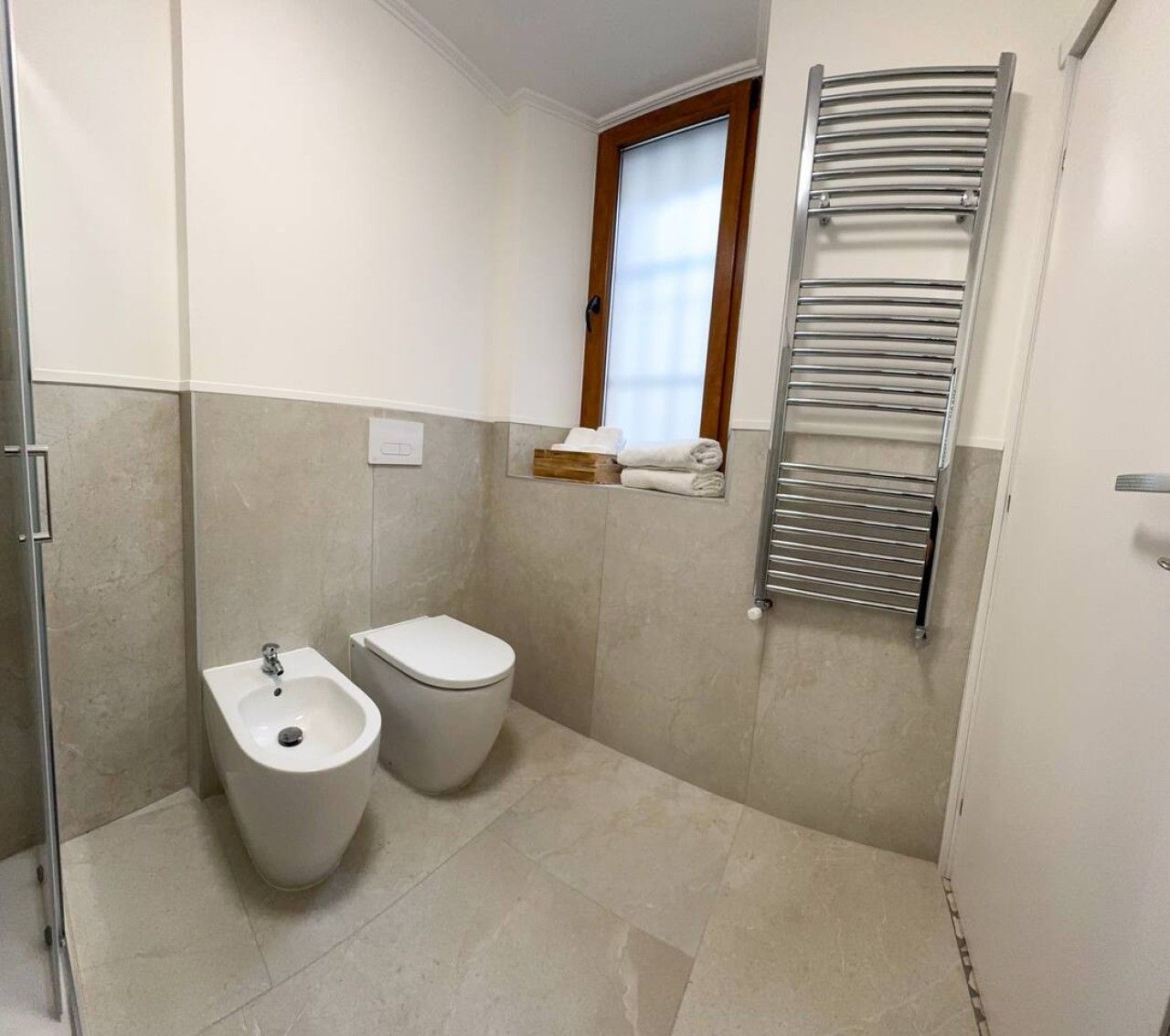 Une salle de bain équipée d’un bidet, de toilettes et d’un porte-serviettes.