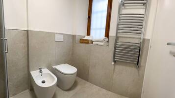 Une salle de bain équipée d’un bidet, de toilettes et d’un porte-serviettes.