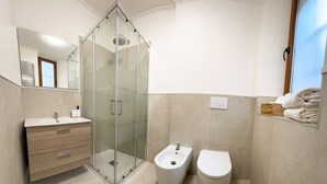 A modern bathroom with a glass-enclosed shower, a bidet, and a toilet. - Fly&Rest MXP | Unit 1 | 24/7 Airport Transfer (Casorate Sempione)