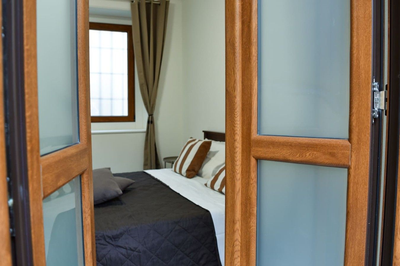 A bedroom with a bed, curtains, and a window.