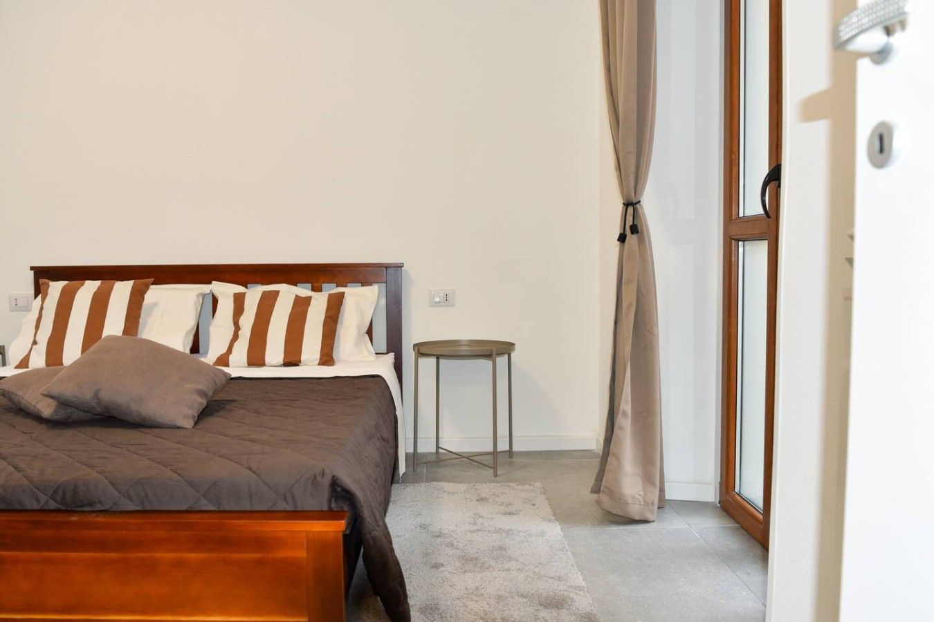 Ein Schlafzimmer mit einem Bett, einem kleinen runden Tisch und einem Fenster mit Vorhängen.