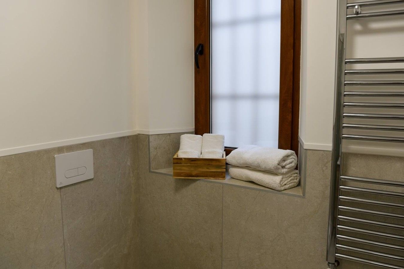 Une salle de bain équipée d’un porte-serviettes, d’un sèche-serviettes et d’une fenêtre avec des rideaux.