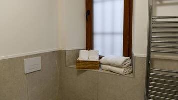 Une salle de bain équipée d’un porte-serviettes, d’un sèche-serviettes et d’une fenêtre avec des rideaux.