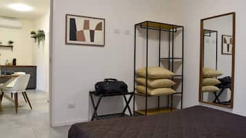Hotellihuone, jossa on sänky, työpöytä, tuoli, vaatekaappi ja peili.