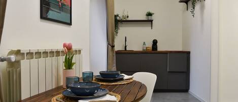 Un comedor con una mesa de madera, sillas y una cocina al fondo.