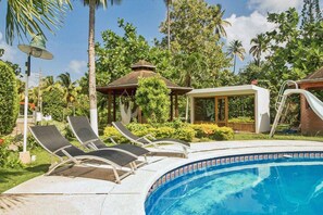 A pool area with lounge chairs, a gazebo, and a covered seating area.