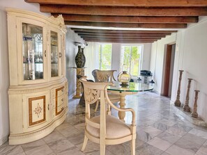 A room with a large cabinet, a round glass table, and a chair.