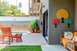 A modern outdoor seating area with wicker chairs and a sofa, a small pool, and decorative wall art. - Casa Linda quase que pe na Areia (Sao Miguel dos Milagres)