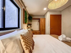 Ein Schlafzimmer mit einem Bett, einem Holzschrank, einem Fenster und einer hängenden Pflanze.