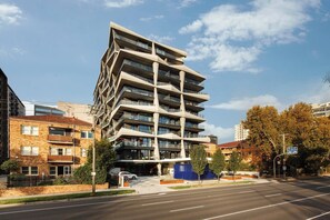 A modern multi-story building with a unique angular design, featuring balconies and large windows. - Lakeside Five star Comfort w Uninterrupted Views (Melbourne)