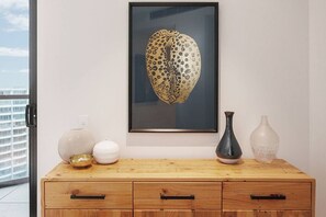 A framed artwork of a leopard's head on a wall, a wooden dresser with drawers, and two vases on the dresser. - Top of Town Penthouse with Every Opulence (Melbourne)