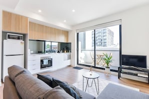 A modern apartment with a kitchen, living area, and a balcony with a city view. - BOWIE Sun soaked Comfort in the Heart of Richmond (Richmond)