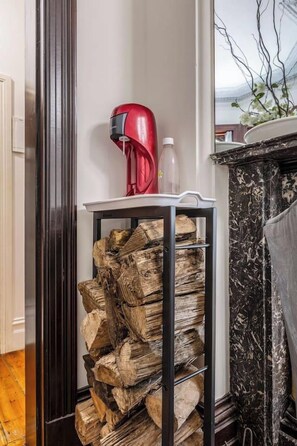 A room with a black metal rack holding firewood, a red hairdryer, and a white bottle on a shelf. - Elwood Manor A Restored Art Deco Gem (Elwood)