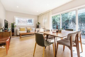 Ein modernes Wohnzimmer mit Essbereich, großen Fenstern und Blick auf Grünflächen.