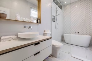 A modern bathroom with a large white sink, a toilet, and a freestanding bathtub. - Classic Comforts Moments to Flemington Racecourse (Flemington)