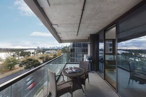 A balcony with a table and chairs, overlooking a cityscape and a river. - Lakeside Lookout Modern Living with Majestic Views (Melbourne)