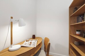 A corner workspace with a desk, a lamp, a chair, a bookshelf, and a small plant. - Lakeside Lookout Modern Living with Majestic Views (Melbourne)