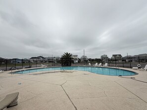 A swimming pool with a curved edge, surrounded by a black fence, and a concrete deck. - Stylish Galveston Island Getaway Near the Beach (Galveston)