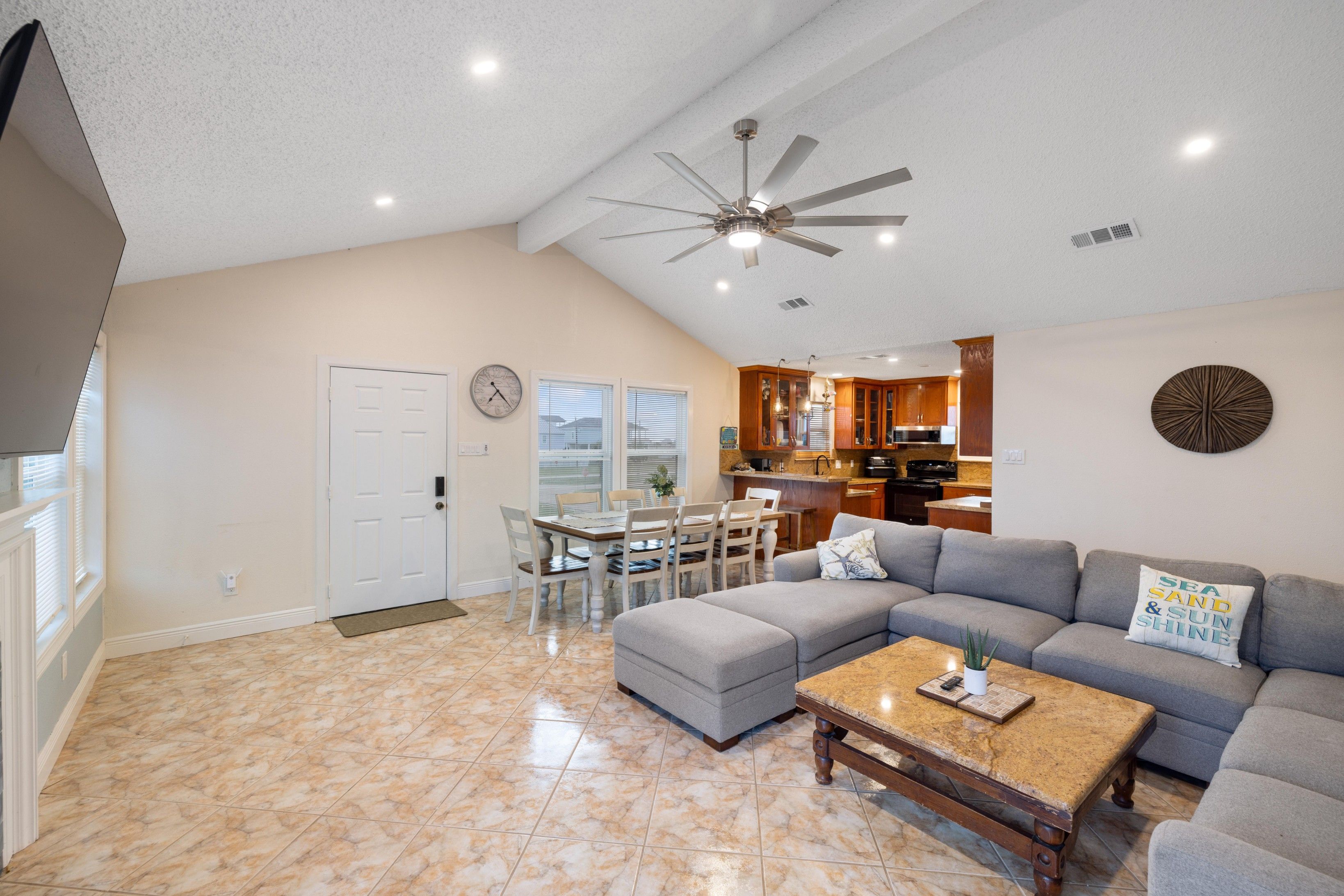 A spacious living room with a large gray sectional sofa, a wooden coffee table, and a ceiling fan.