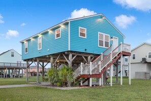 A two-story house with a wooden deck and a staircase leading to the upper floor. - Stylish Galveston Island Getaway Near the Beach (Galveston)
