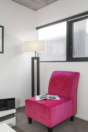 A room with a bright window, a floor lamp, a pink chair, and a white side table. - Refresh at Rhapsody City Fringe Contemporary (Melbourne)