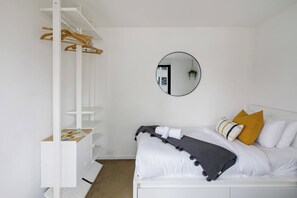 A bedroom with a bed, a white wardrobe, a mirror, and a hanging plant. - Metropolis Icon Bourke Street Heritage Hideaway (Melbourne)