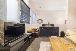 A modern living room with a flat-screen TV, a dark-colored sofa, a wooden coffee table, and a decorative rug. - Hikari Haven Richmonds Creative Spirit near Cafs (Richmond)