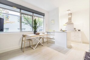 A modern kitchen with a dining area, large windows, and a view of the outside. - The Courtyard Chateau Fresh and Modern off Toorak Rd (South Yarra)