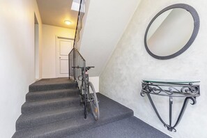 A staircase with a bicycle leaning against the railing, a wall-mounted mirror, and a glass shelf with decorative metalwork. - The Courtyard Chateau Fresh and Modern off Toorak Rd (South Yarra)