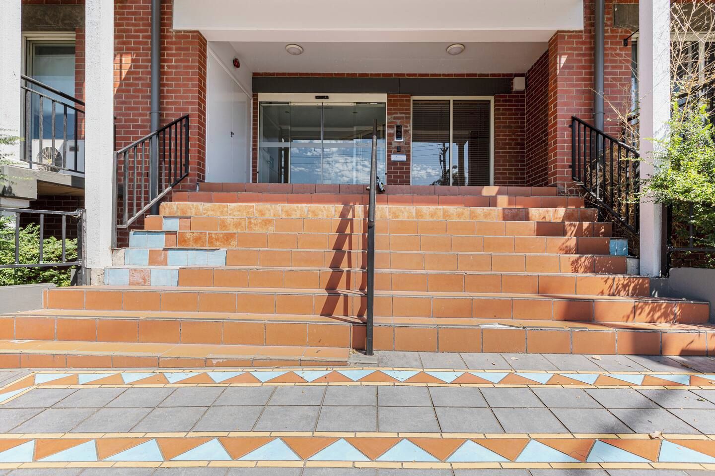 A building entrance with a set of outdoor stairs leading up to a glass door.