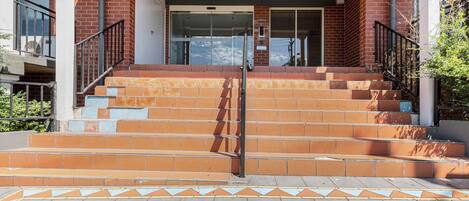 A building entrance with a set of outdoor stairs leading up to a glass door.