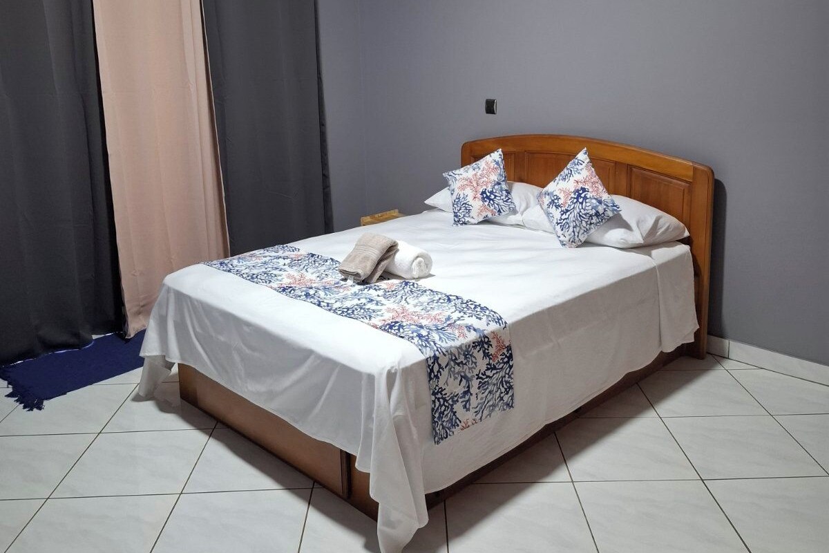 A hotel room with a bed, curtains, and a tiled floor.