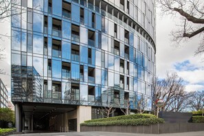 A modern building with a curved facade, large windows, and a landscaped entrance area. - Parque Canopy Lakeside Living with Infinity Pool (Melbourne)