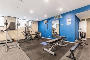 A gym with exercise equipment, a mirror, and a blue wall. - Nottville Poolside Coastal Cosmopolitan off Bay St (Port Melbourne)