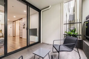 A modern interior with a sliding glass door leading to a living area, a small table, and a chair. - Nottville Poolside Coastal Cosmopolitan off Bay St (Port Melbourne)