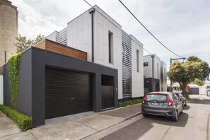 Ein modernes Wohngebäude mit Garage, ein Auto davor und ein Baum in der Nähe.