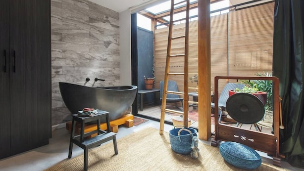 Un bany modern amb una banyera autònoma, una escala de fusta i vista a una zona d'estar exterior.