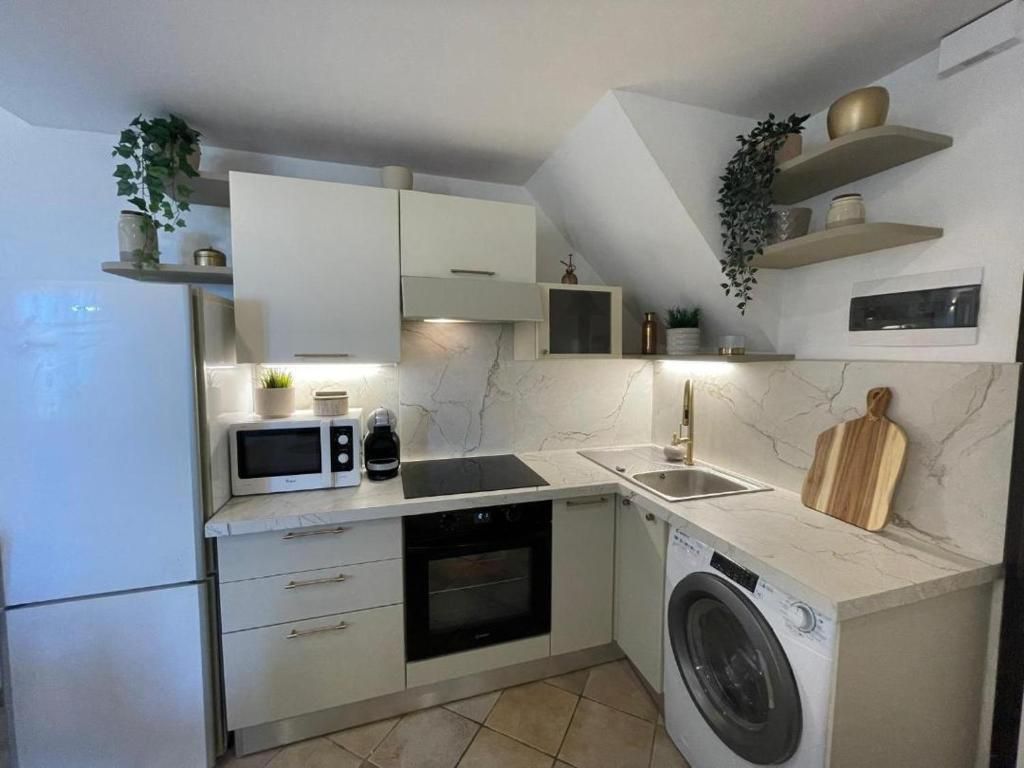 A compact kitchen with a built-in oven, microwave, and washing machine.