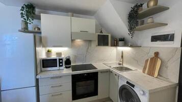 A compact kitchen with a built-in oven, microwave, and washing machine.
