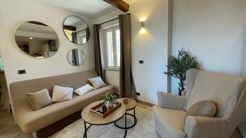 Una sala de estar con sofá, sillón, mesa de centro y espejos decorativos.