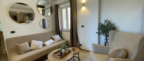 A living room with a sofa, armchair, coffee table, and decorative mirrors.