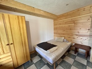 A bedroom with a bed, a wooden wardrobe, and a small bedside table. - 300 meters from the ski slopes, patio, 120 m², Vars (Vars)