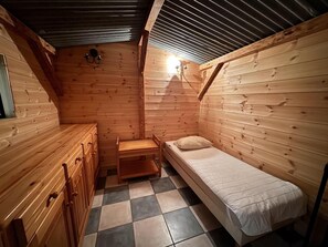 Ein kleines Zimmer einer Holzhütte mit einem Bett, einer Bank und einem kleinen Tisch.