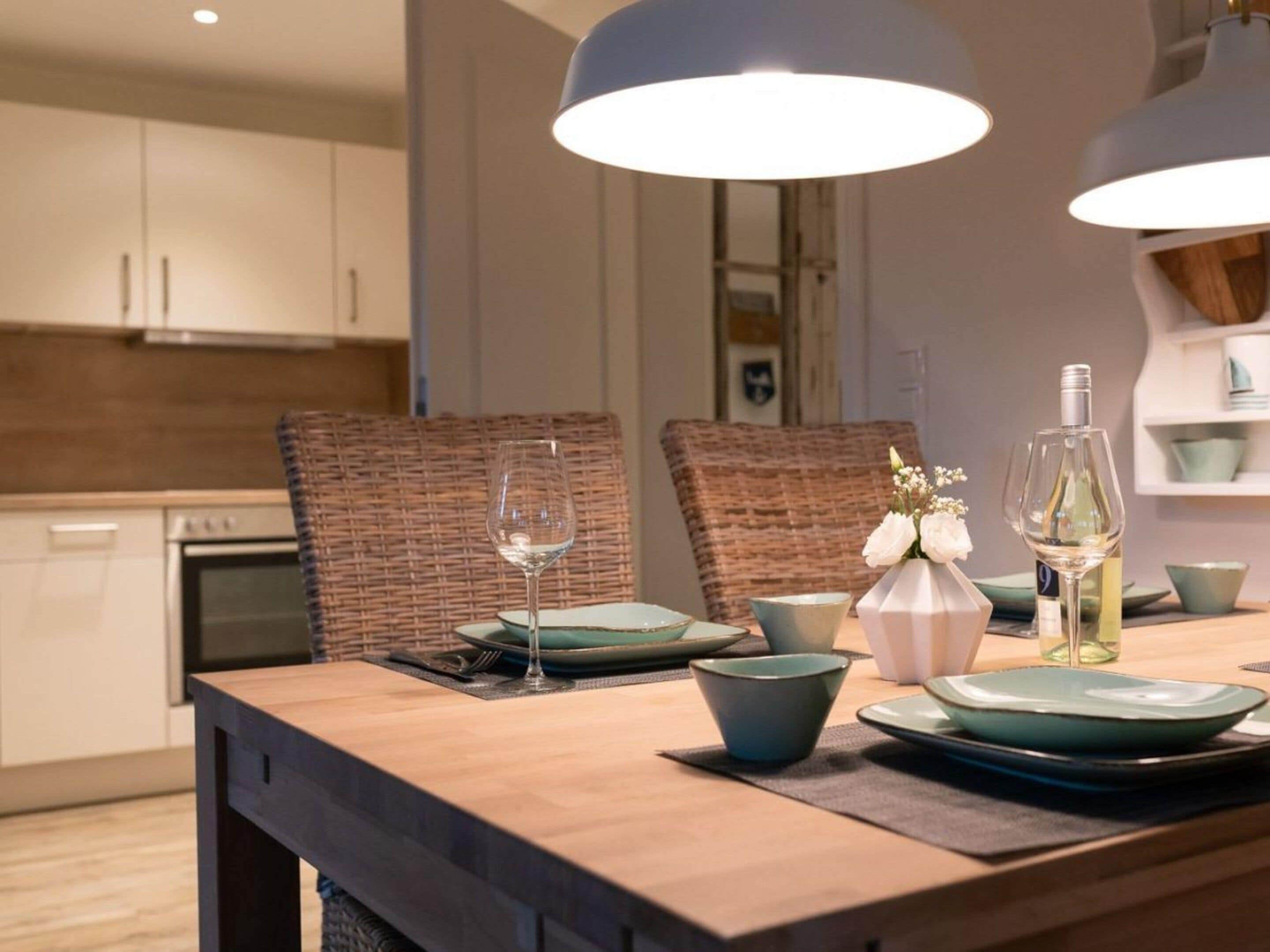 Una cocina moderna con una mesa de comedor de madera, sillas de mimbre e iluminación colgante.