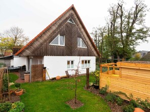 Ein zweistöckiges Haus mit geneigtem Dach, einem kleinen Vorgarten und einem Holzzaun.